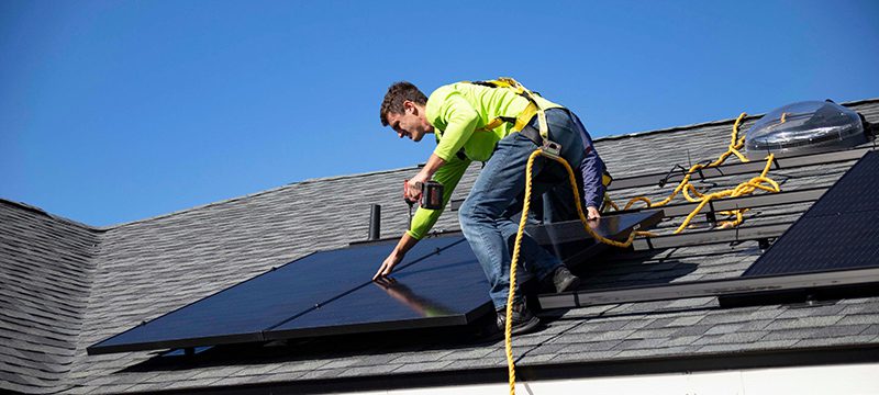 a man on a roof with a solar panel