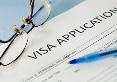 Visa papers next to a pen and glasses