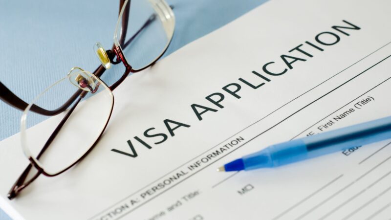 Visa papers next to a pen and glasses